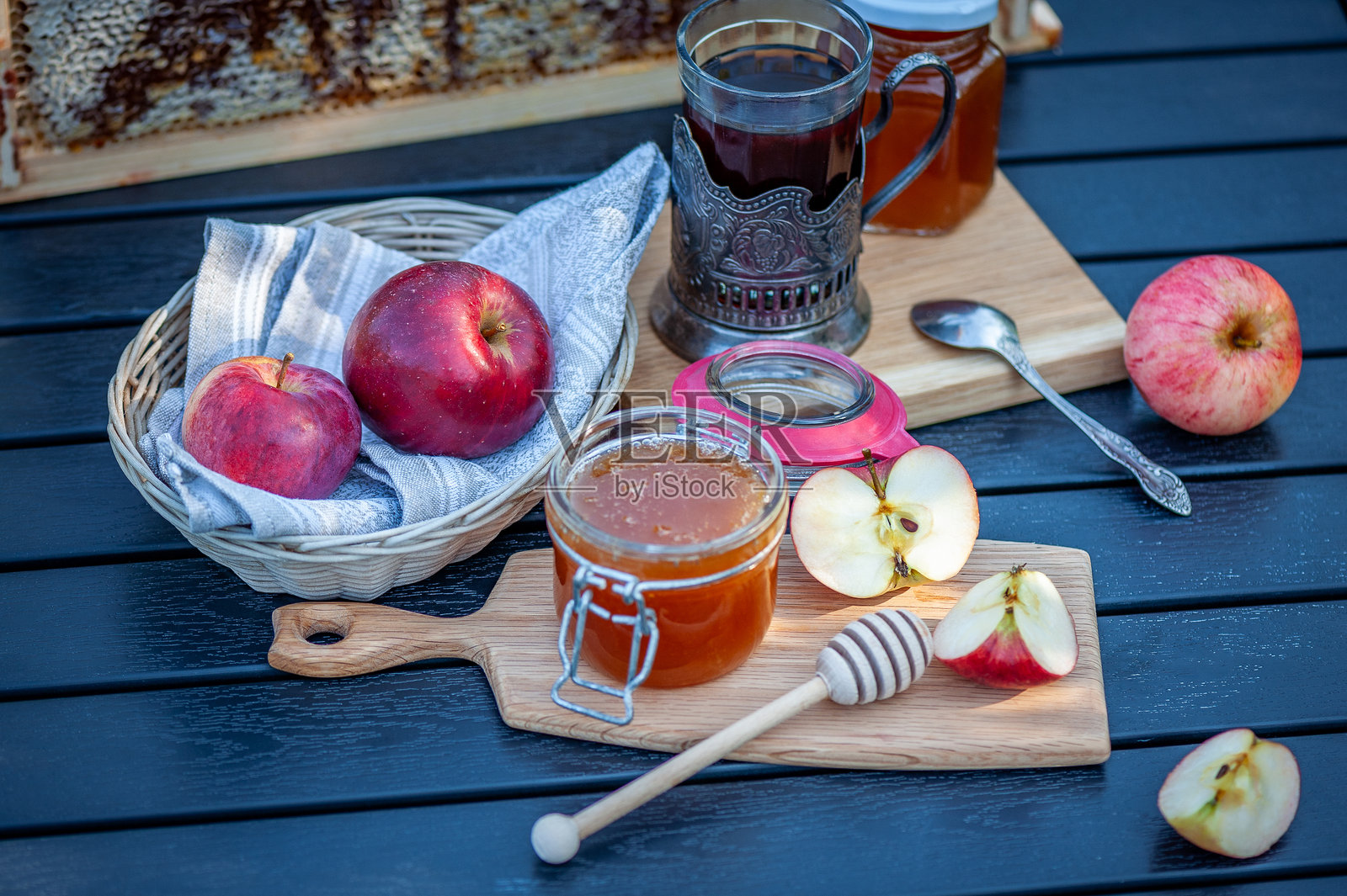 有机蜂蜜和苹果摆放在木板上，淋着糖浆，背景是花园照片摄影图片