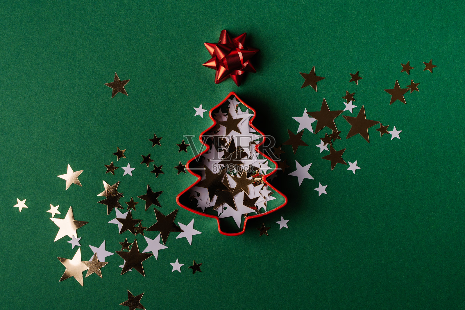 圣诞树饼干模具和星星纸屑在绿色背景上照片摄影图片