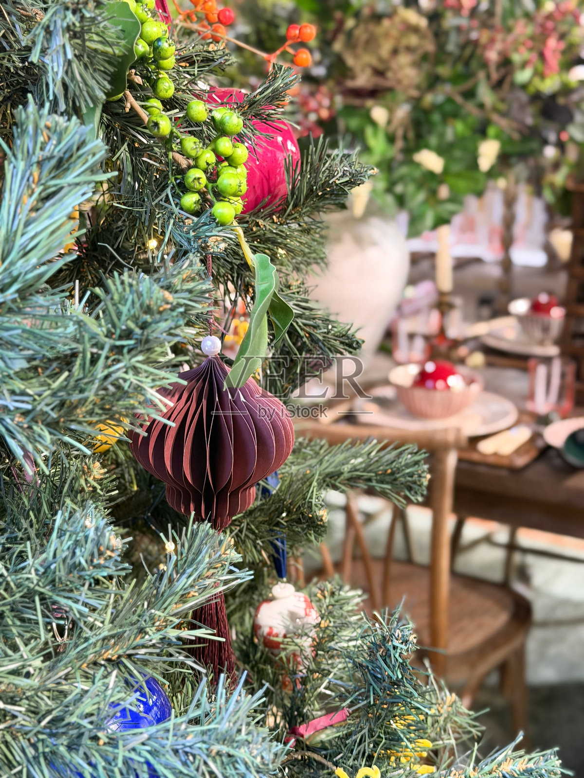 装饰有饰品的仿真圣诞树，旁边是餐桌和椅子，突显节日室内风格照片摄影图片