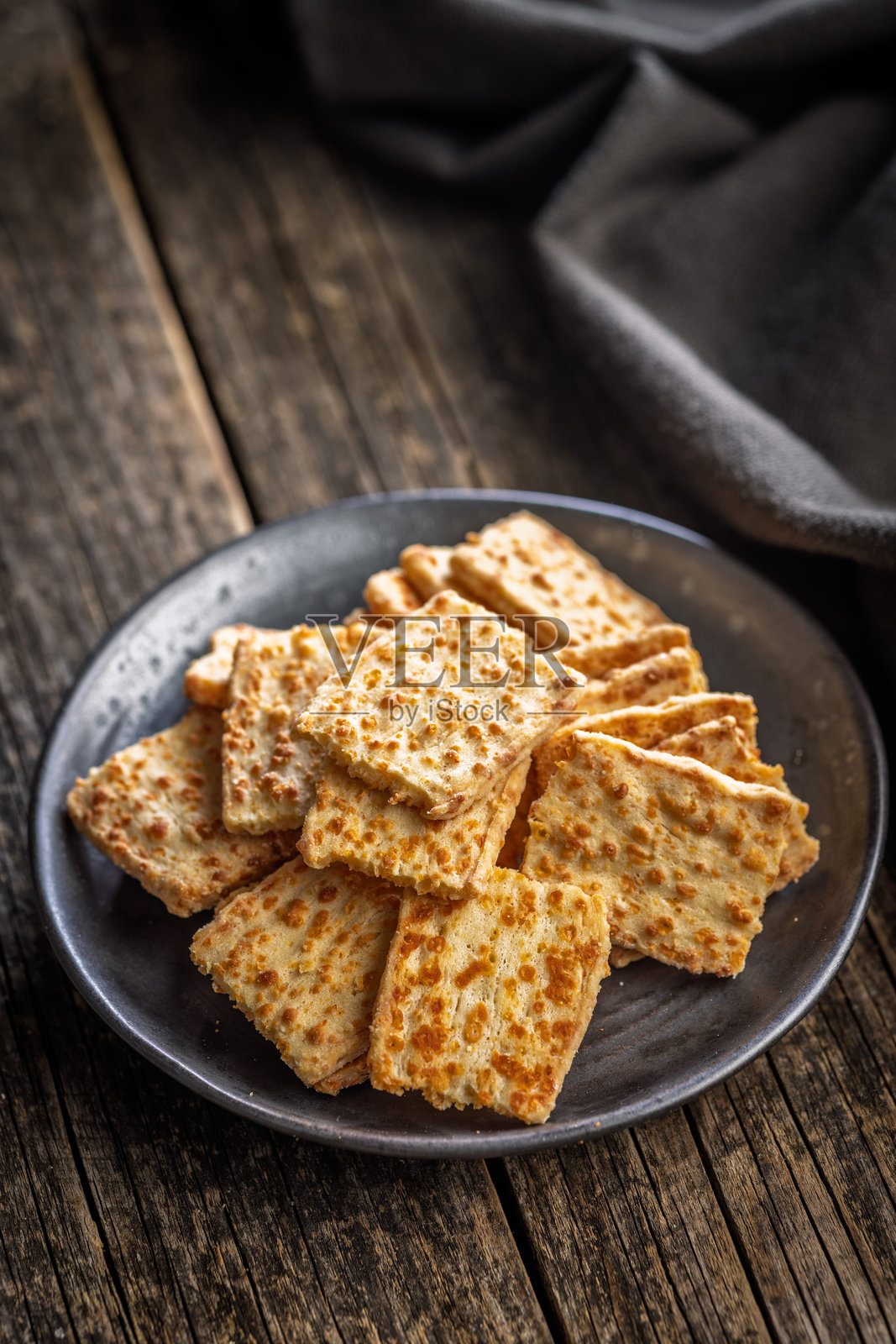 木桌上的盘子里放着香脆的咸味饼干。照片摄影图片