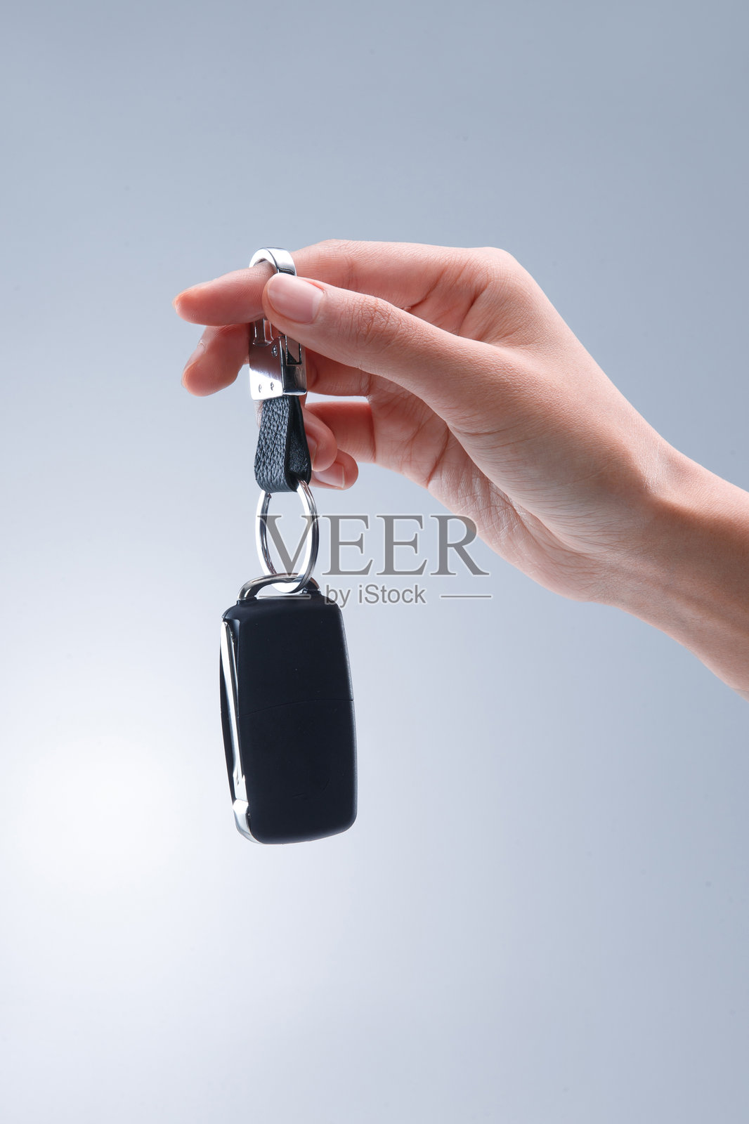 蓝底背景上手持车钥匙照片摄影图片