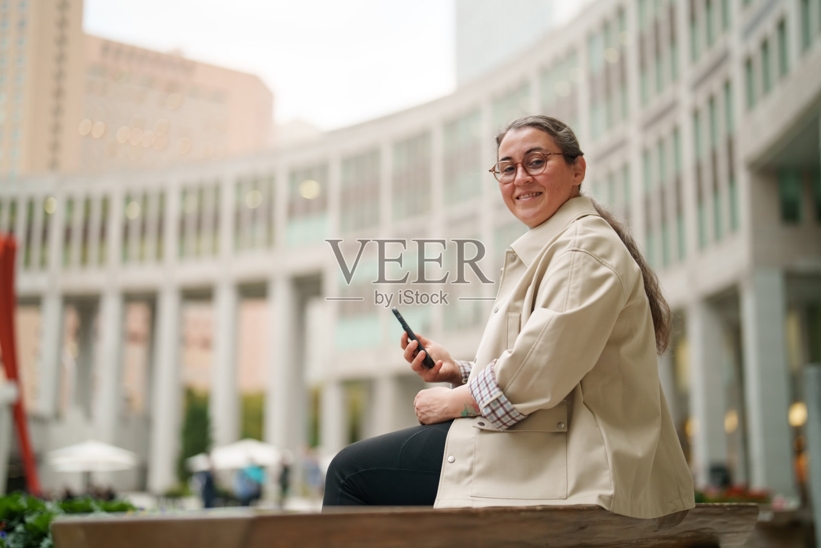 一位女士在现代城市广场户外使用智能手机照片摄影图片