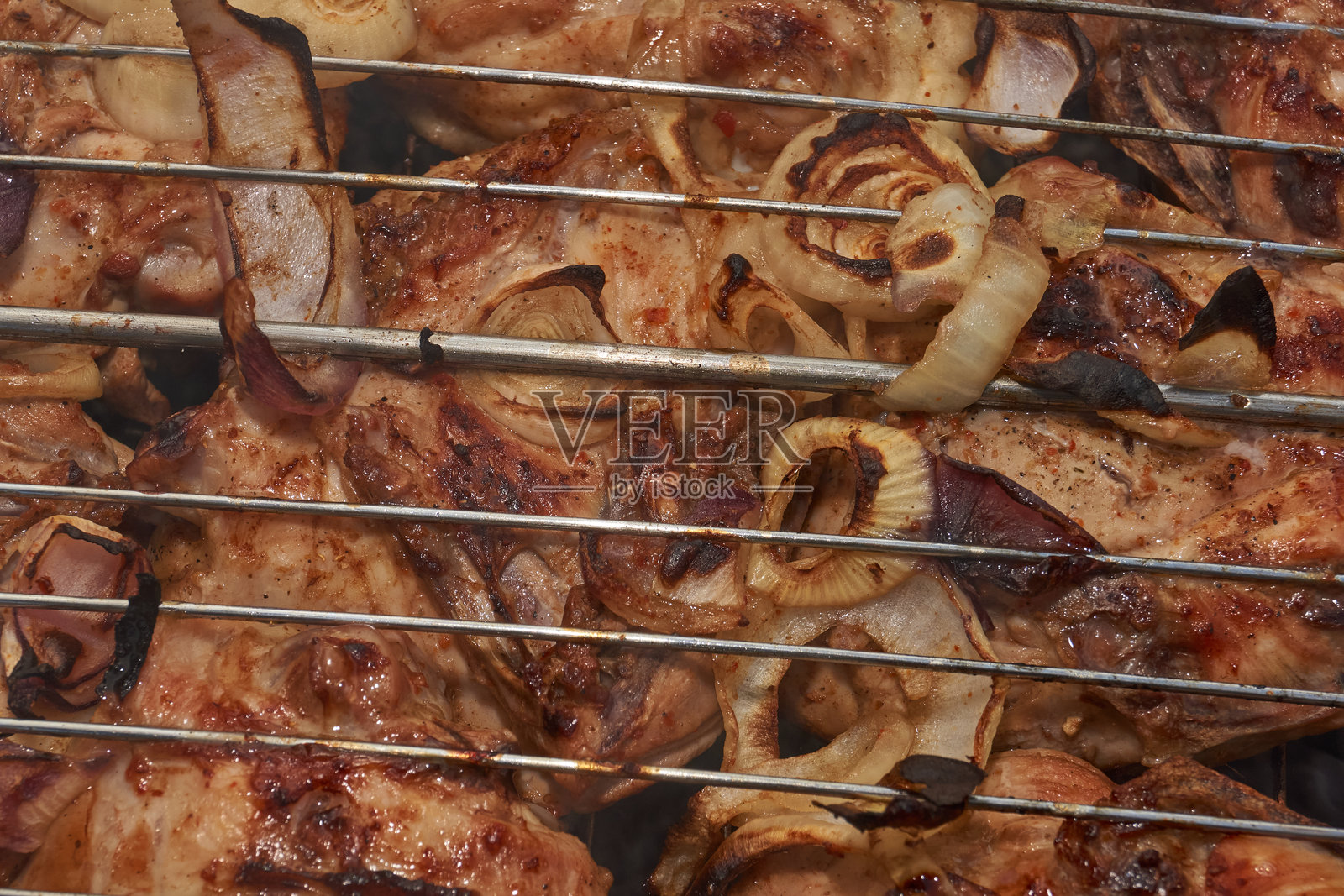 金黄酥脆的炸鸡块在炭火烤架上烤制。照片摄影图片