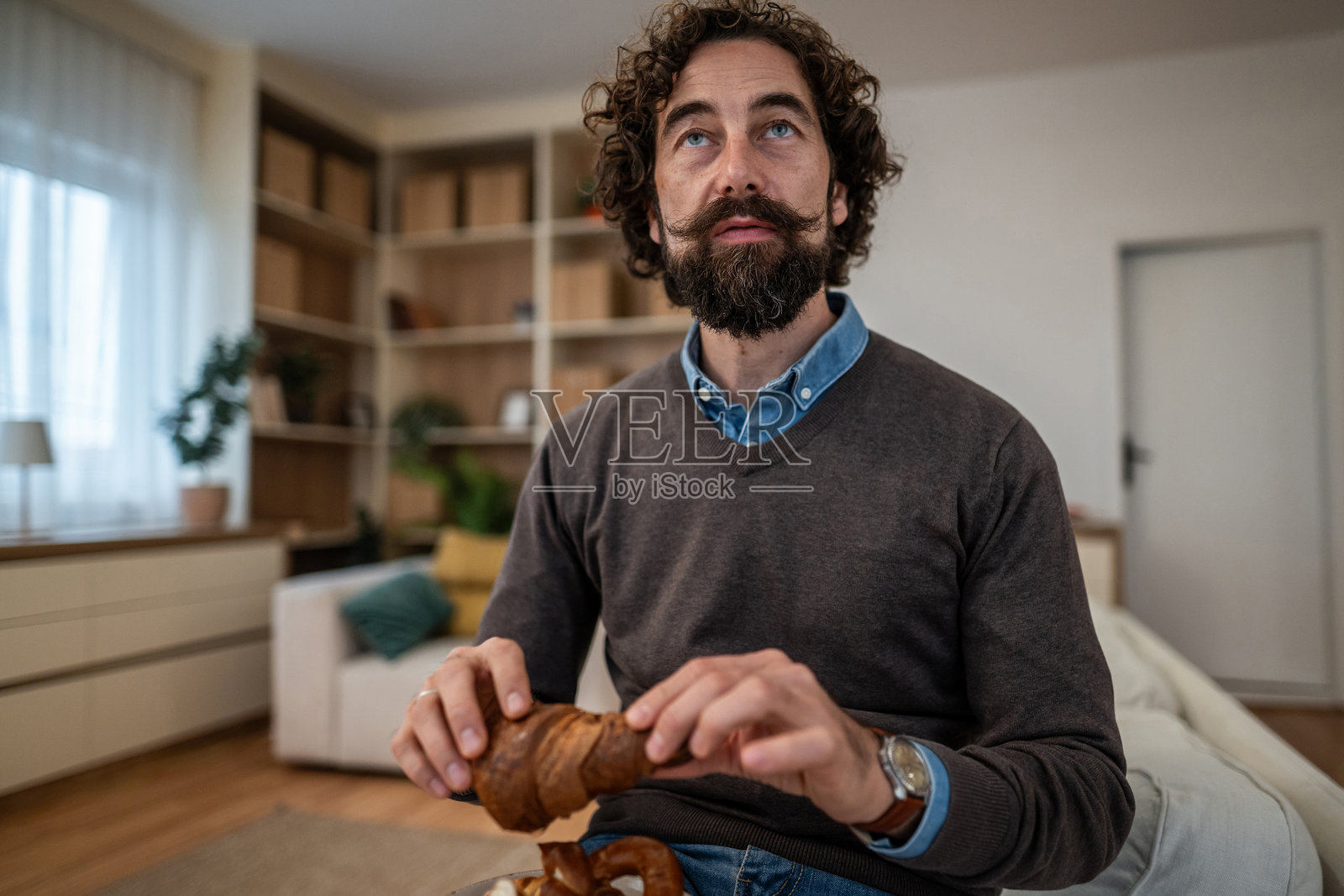 男人在吃早餐羊角面包时胡思乱想照片摄影图片