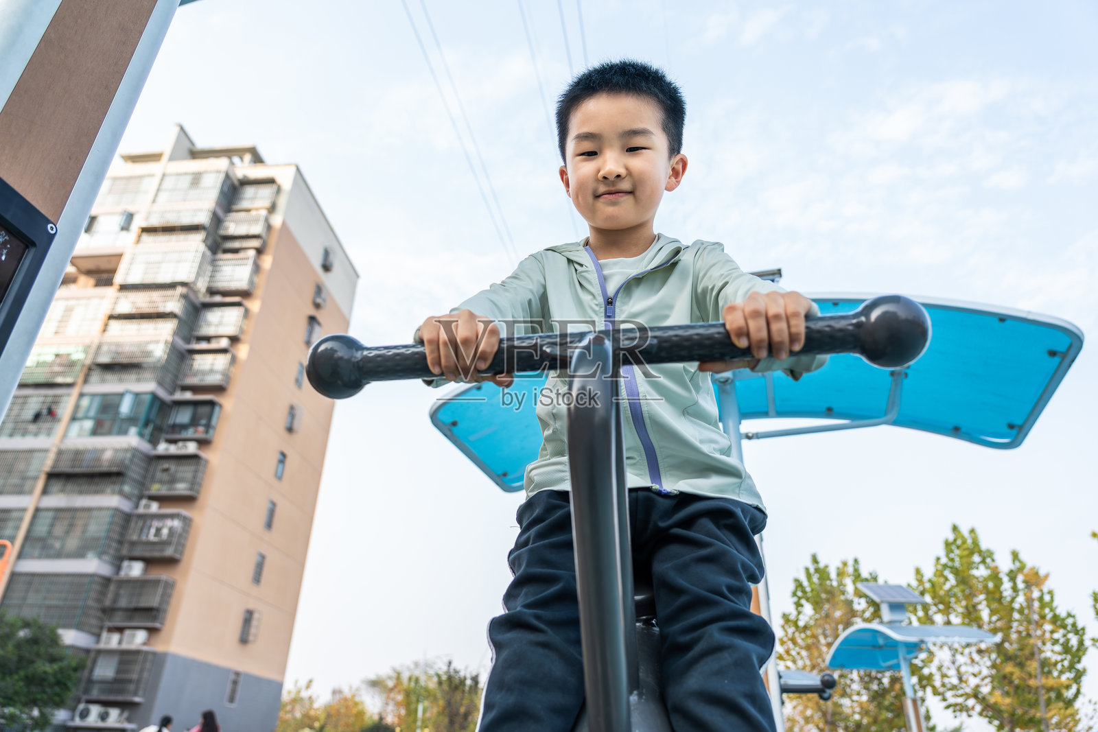 小男孩在社区的户外健身器材上锻炼照片摄影图片