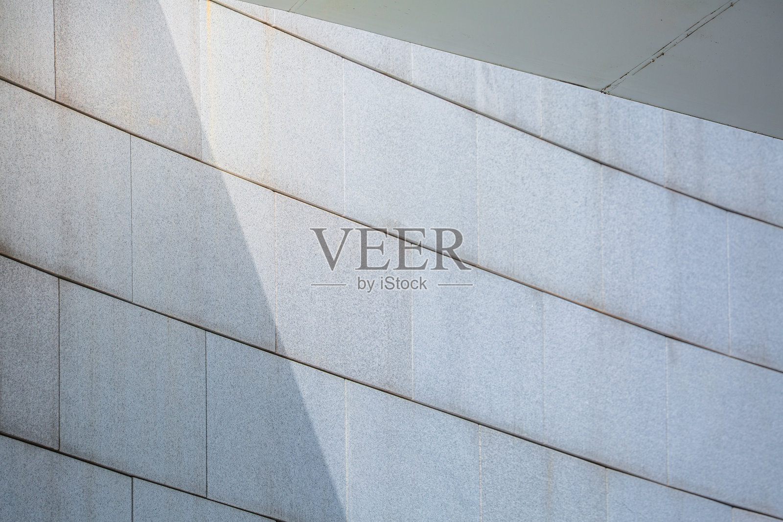 现代建筑的弧形石墙，光影交错照片摄影图片