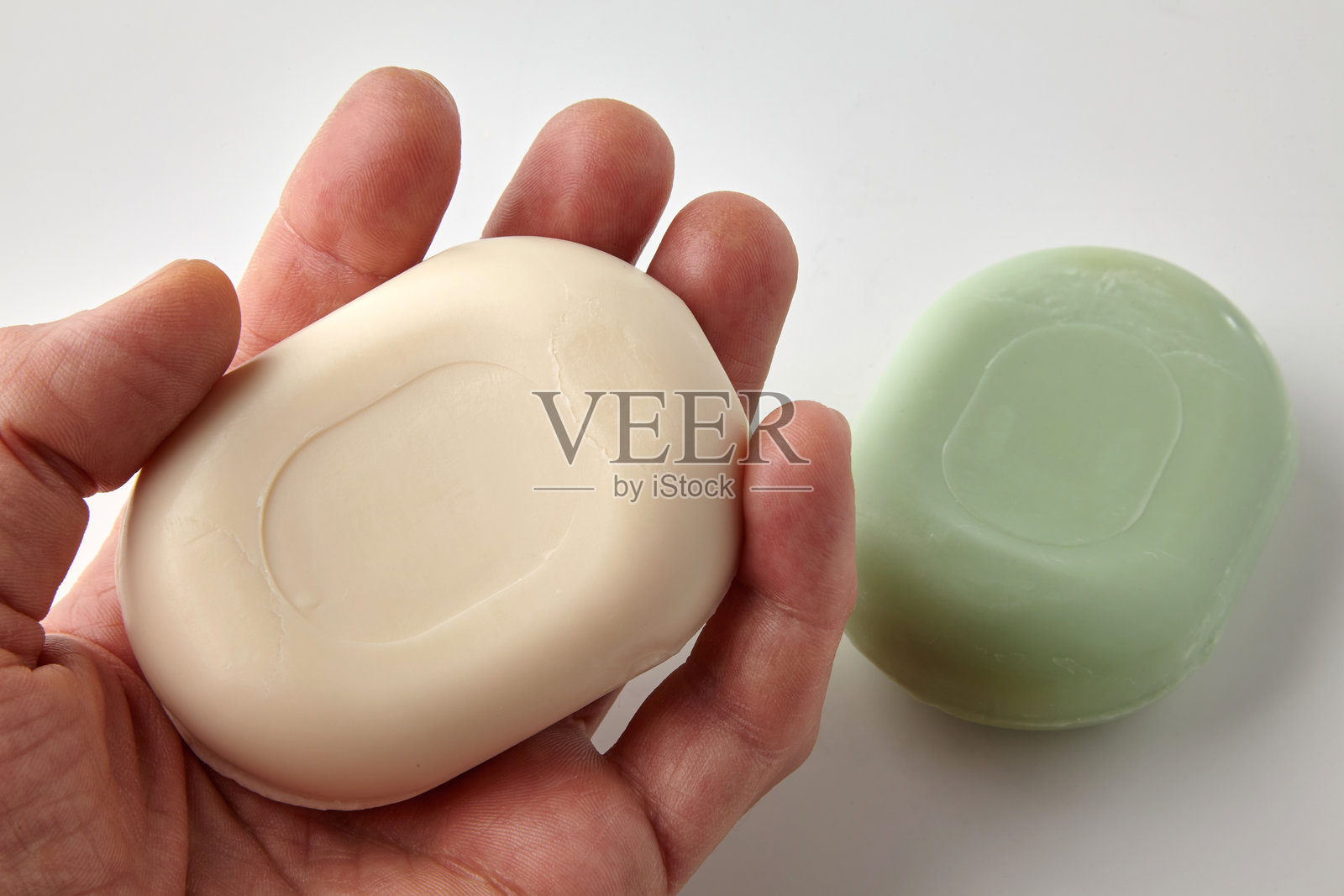 手中散发着香味的白色马桶皂。绿色肥皂的俯视图。照片摄影图片