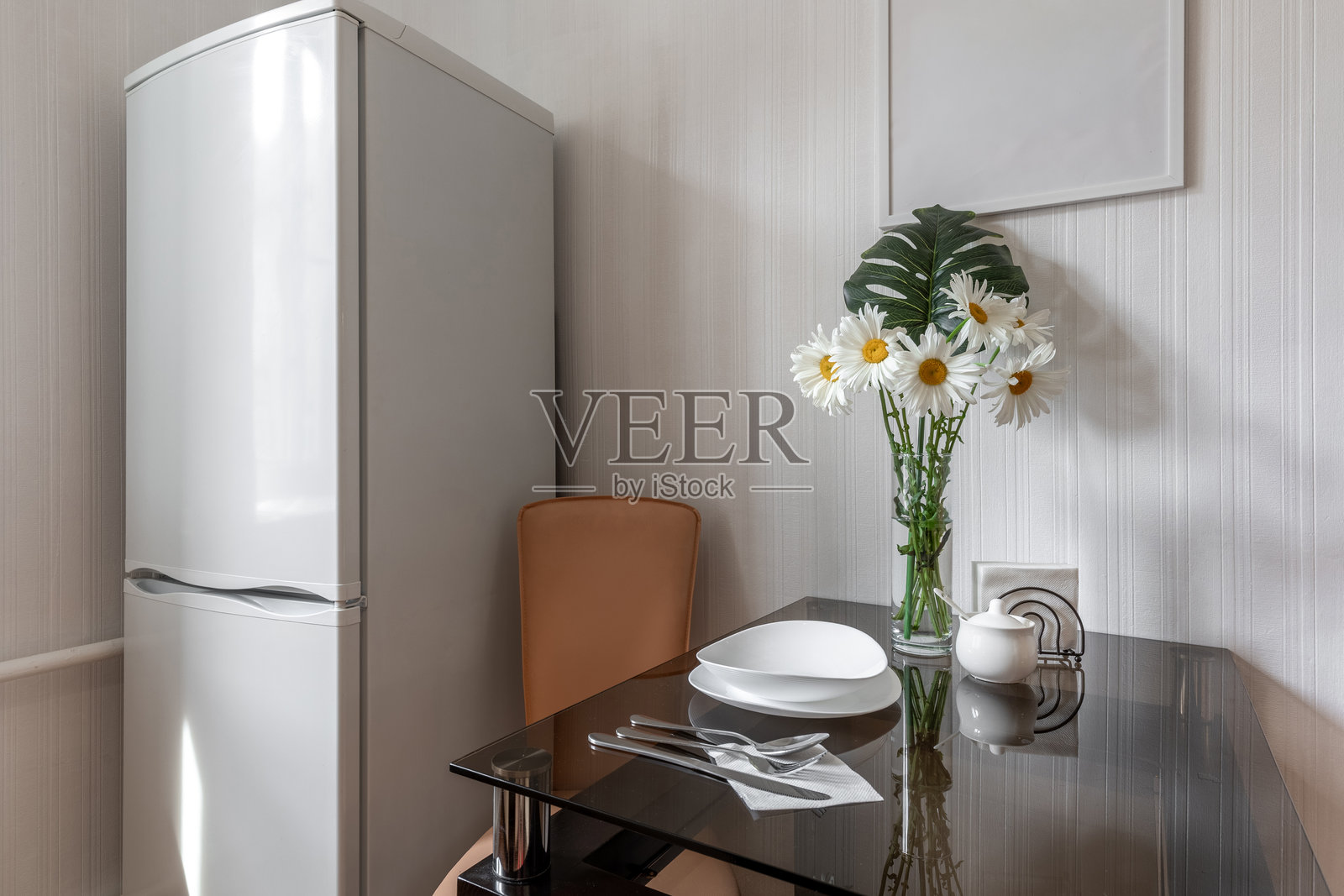 明亮的厨房角落，配有冰箱和玻璃桌照片摄影图片