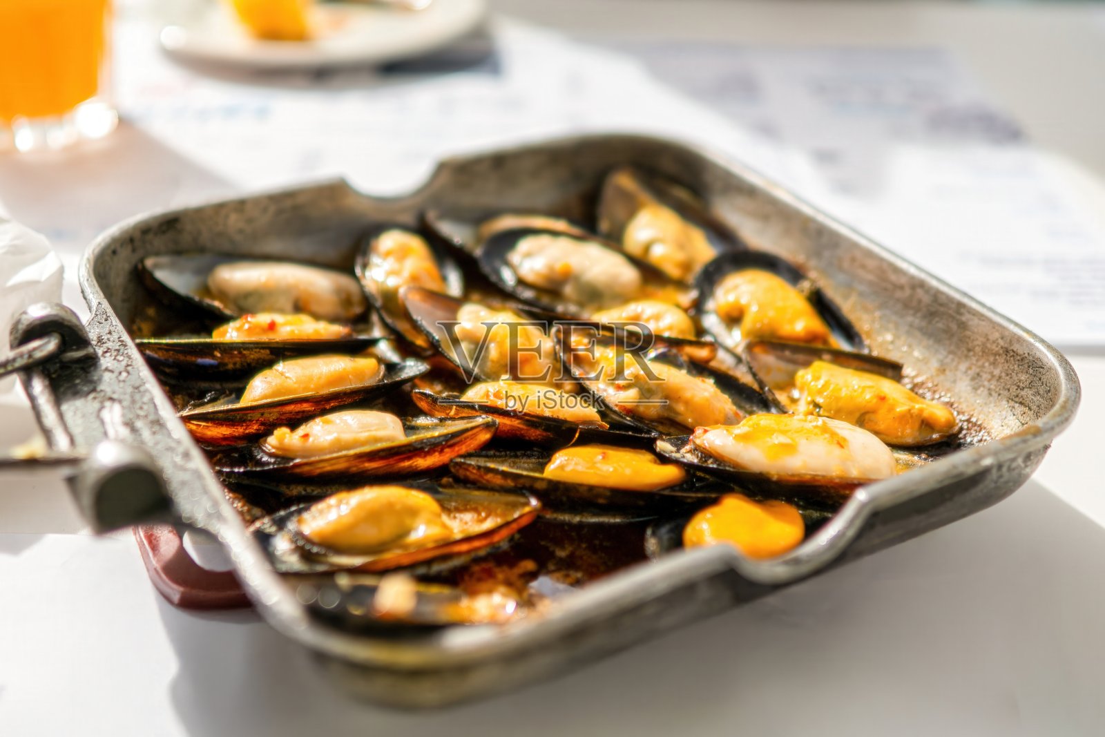新鲜烹制的贻贝配酱汁，盛放在金属锅中照片摄影图片