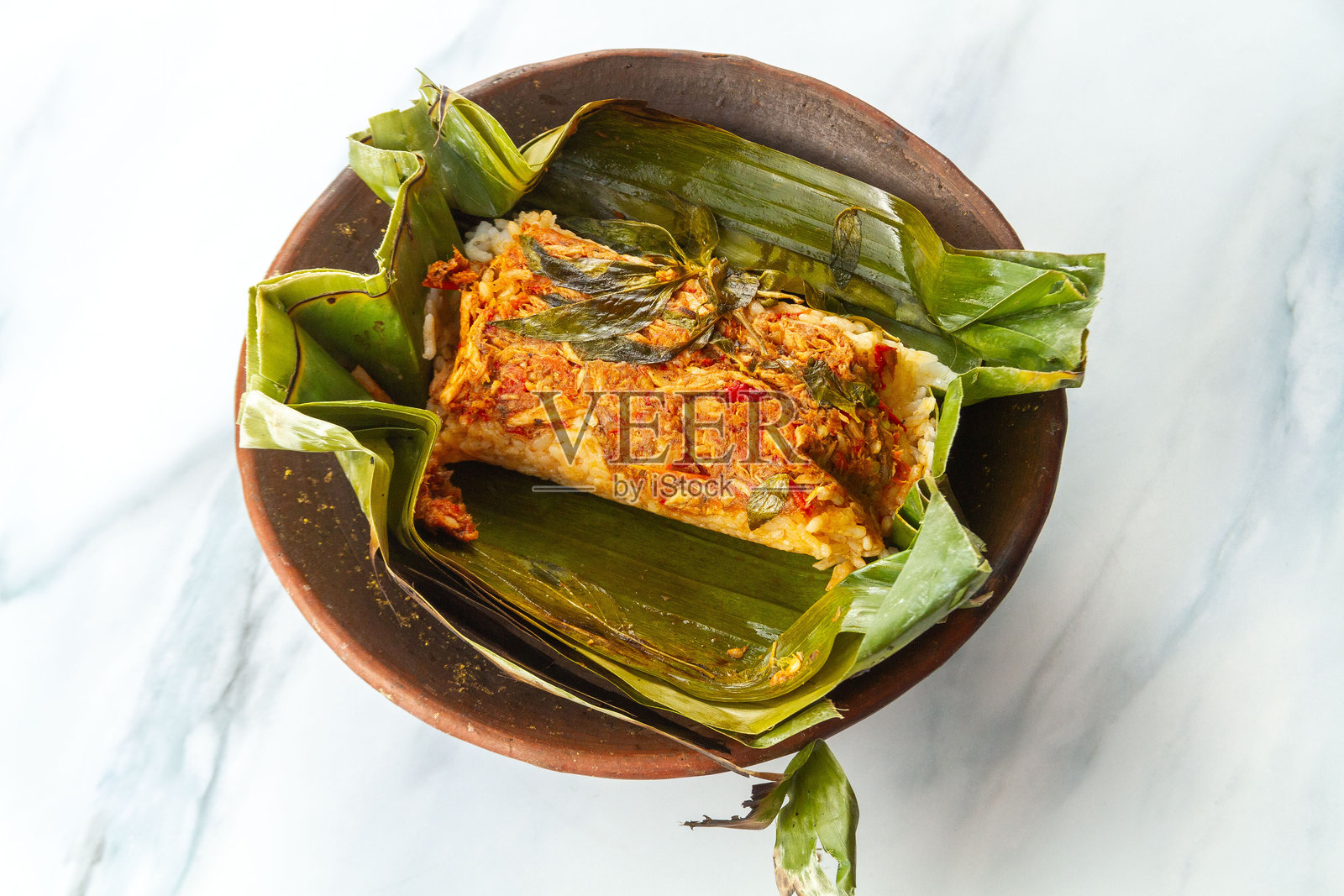 香蕉叶烤饭，置于大理石背景上，这是用木炭烤制的传统印尼菜肴，内含海鲜、肉类或鸡肉馅料。照片摄影图片