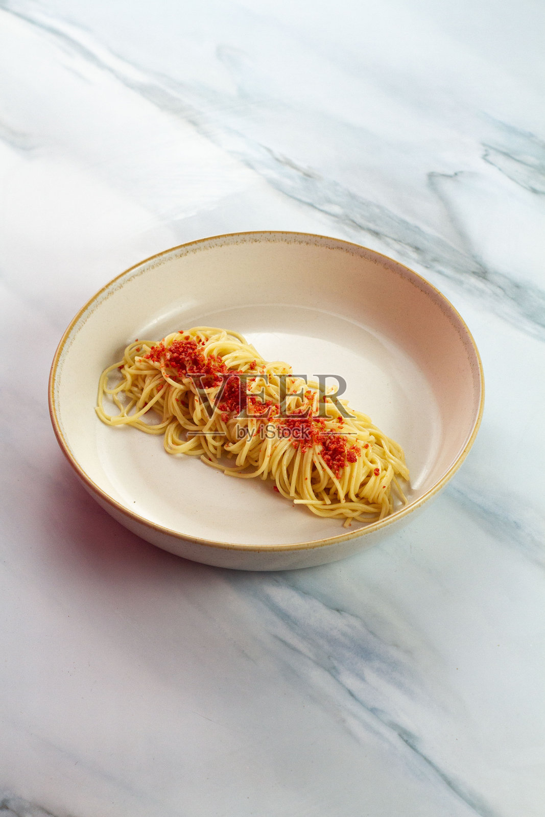 自制蒜香意面配大蒜、酥脆的辣椒片和帕玛森芝士，盛在白盘中，这是一道美味的意大利面食。照片摄影图片