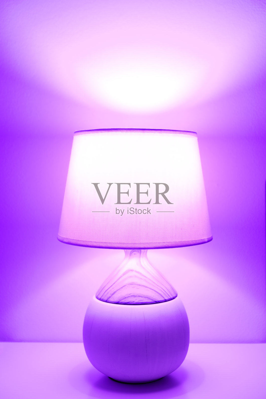 时尚现代台灯，带有织物灯罩，在霓虹紫光下发光。照片摄影图片