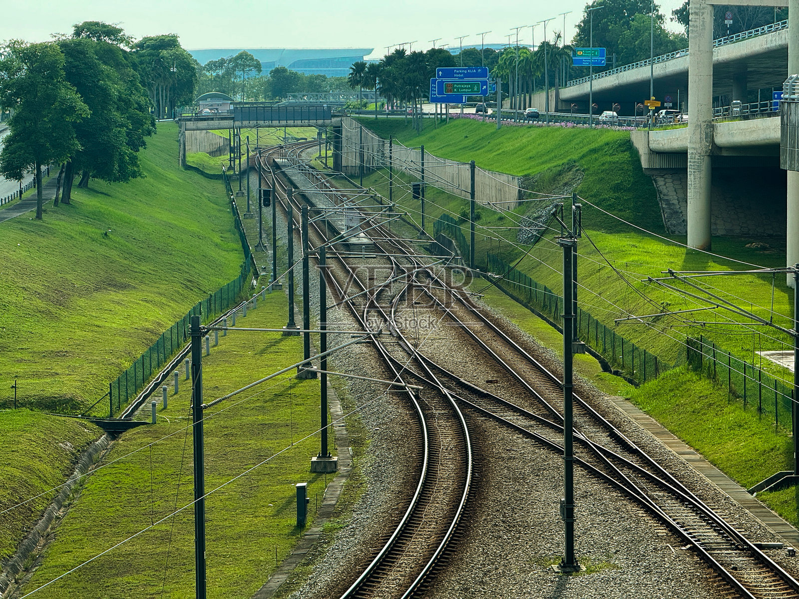 俯视视角，铁路道岔在郁郁葱葱的绿色堤岸和公路基础设施之间汇合照片摄影图片