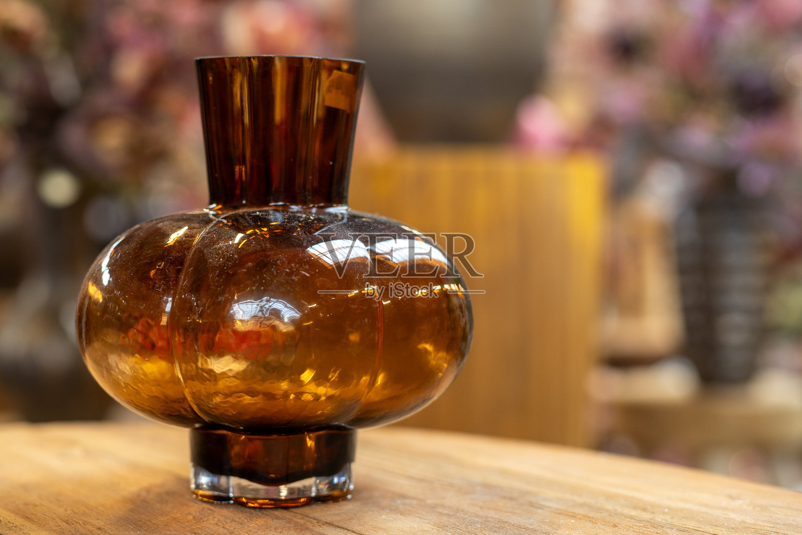 木桌上的琥珀色玻璃花瓶，带有温暖的散景照片摄影图片