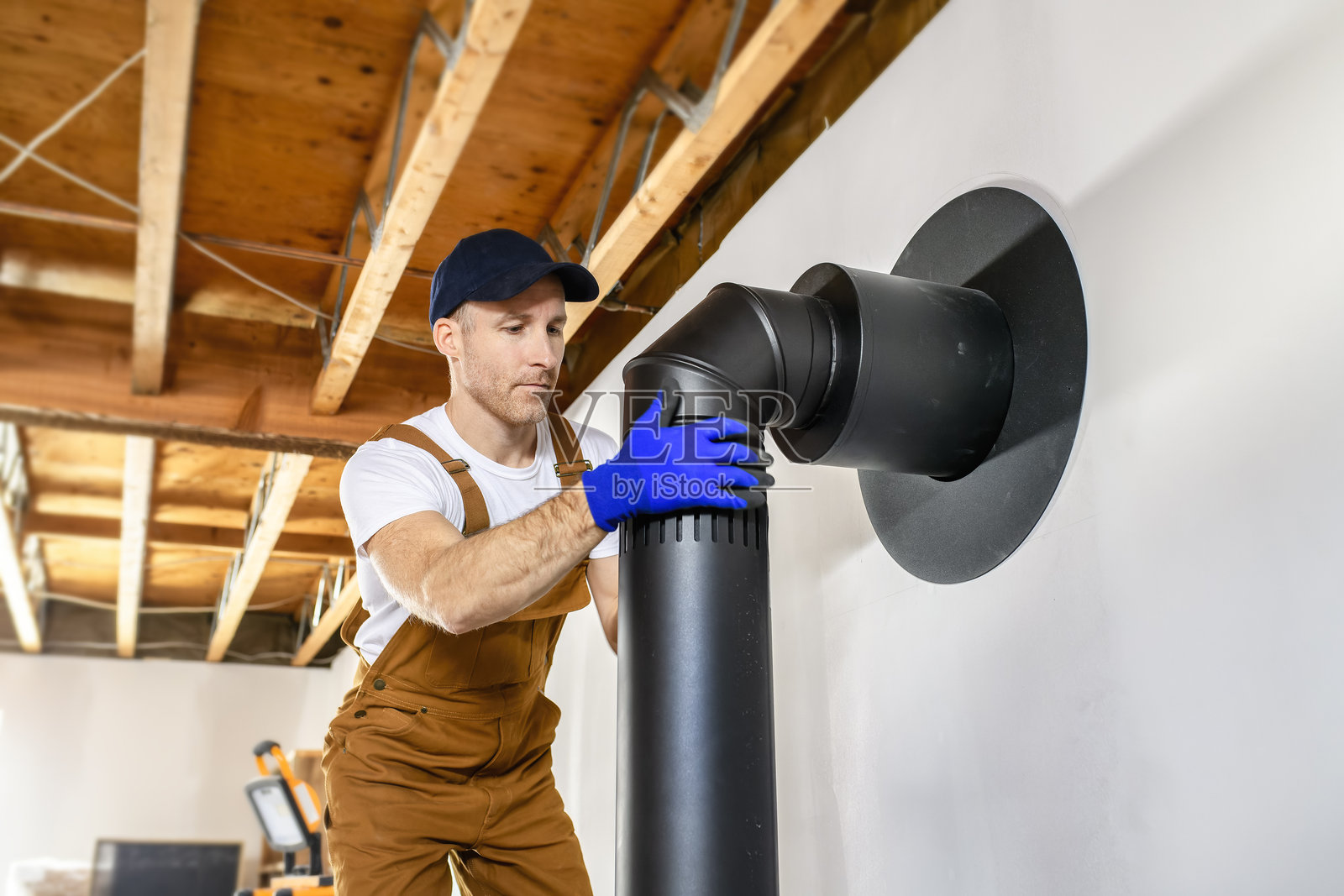 男工正在为安装现代节能暖炉准备烟囱照片摄影图片