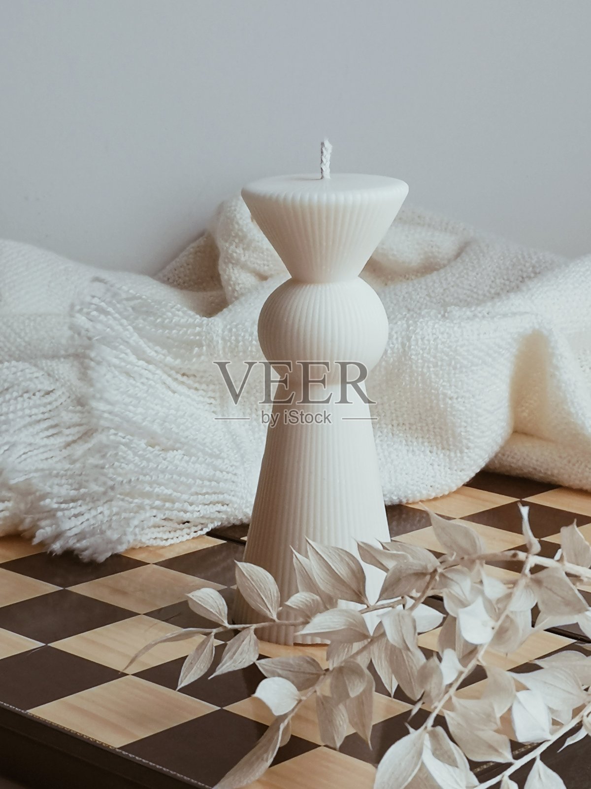 摆放在木质国际象棋棋盘上的优雅白色兵形蜡烛圣诞装饰品照片摄影图片