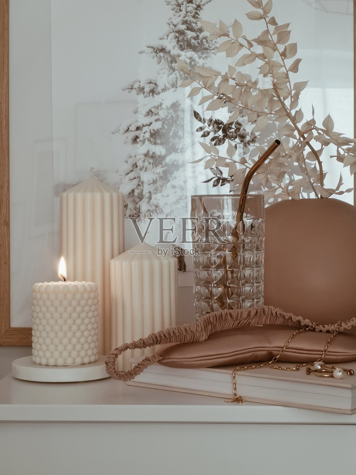 优雅的白色点燃蜡烛套装圣诞装饰，摆放在带有植物和玻璃杯的桌子上照片摄影图片