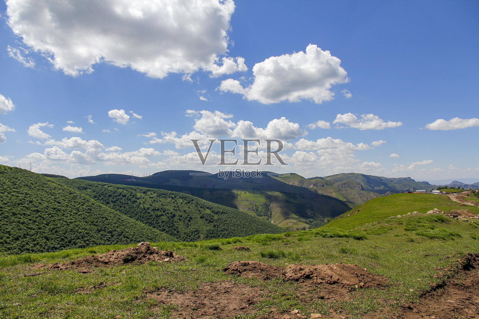 晴朗的蓝天下，白云朵朵，翠绿的山峦连绵起伏照片摄影图片