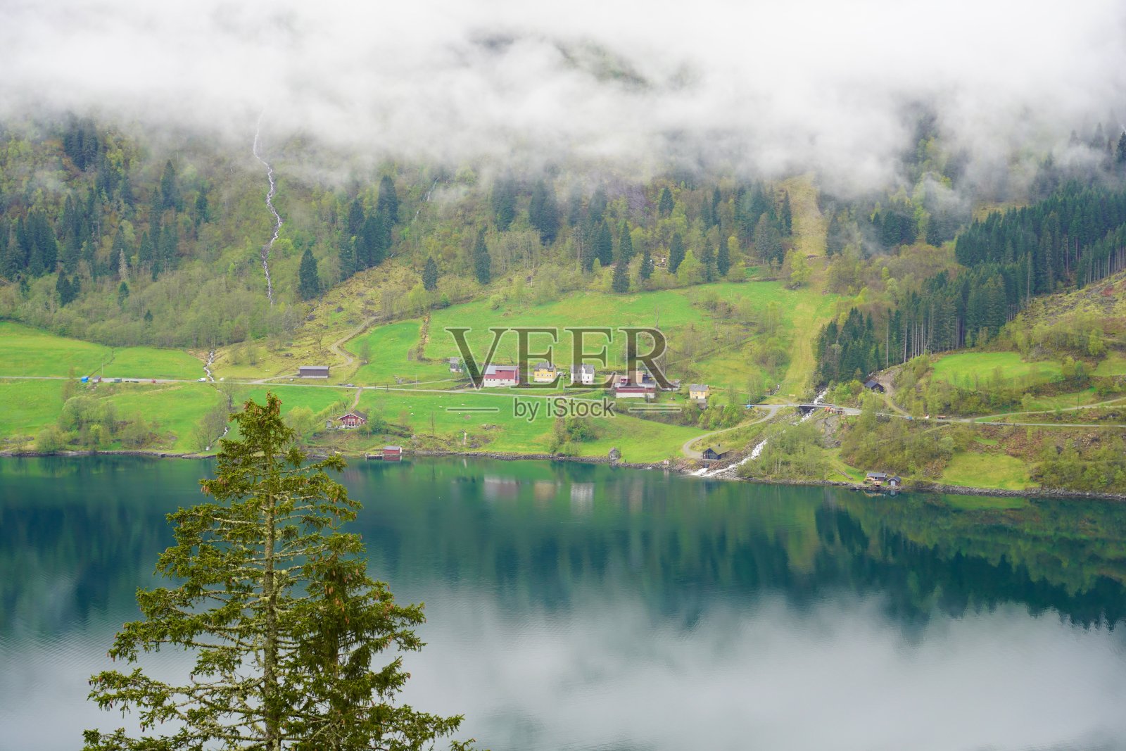 薄雾笼罩的山间湖泊倒映着村庄照片摄影图片