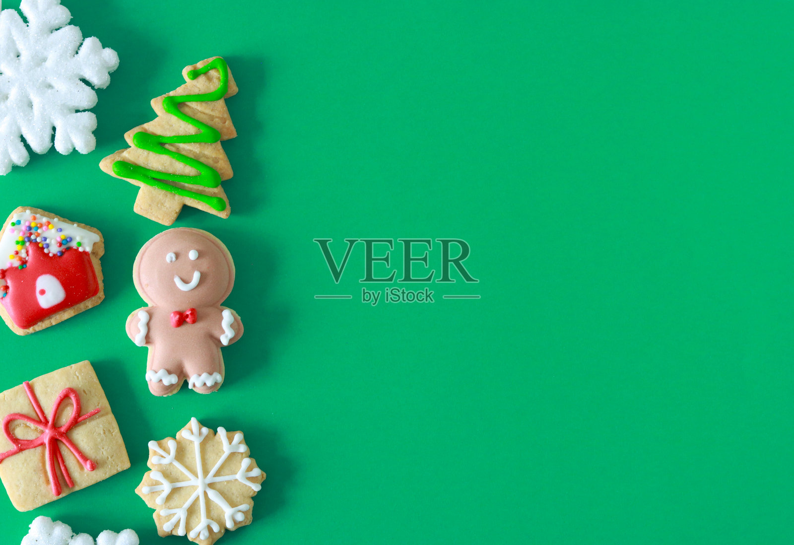节日圣诞饼干和雪花在绿色背景上，布局干净，留有充足的空间用于假日信息或设计元素。照片摄影图片