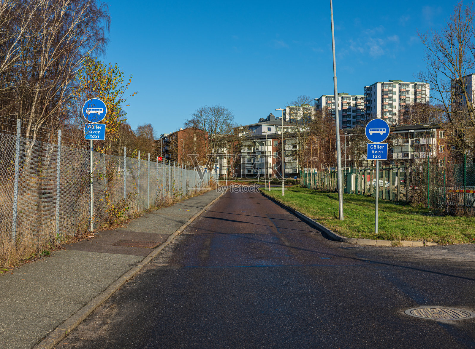 城市道路设有公交专用道标志，通往公寓楼。照片摄影图片