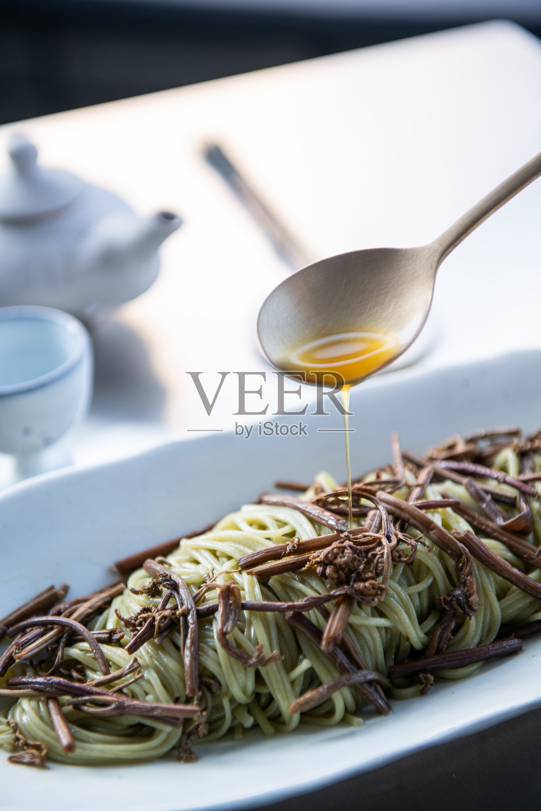 白盘子里的意大利面配橄榄油和勺子。照片摄影图片