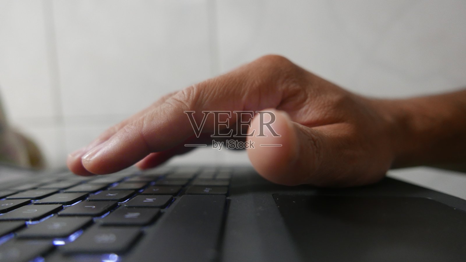 一个人在笔记本电脑键盘上打字。一台电脑键盘。一个QWERTY键盘。写作时间。工作。家庭办公室。照片摄影图片