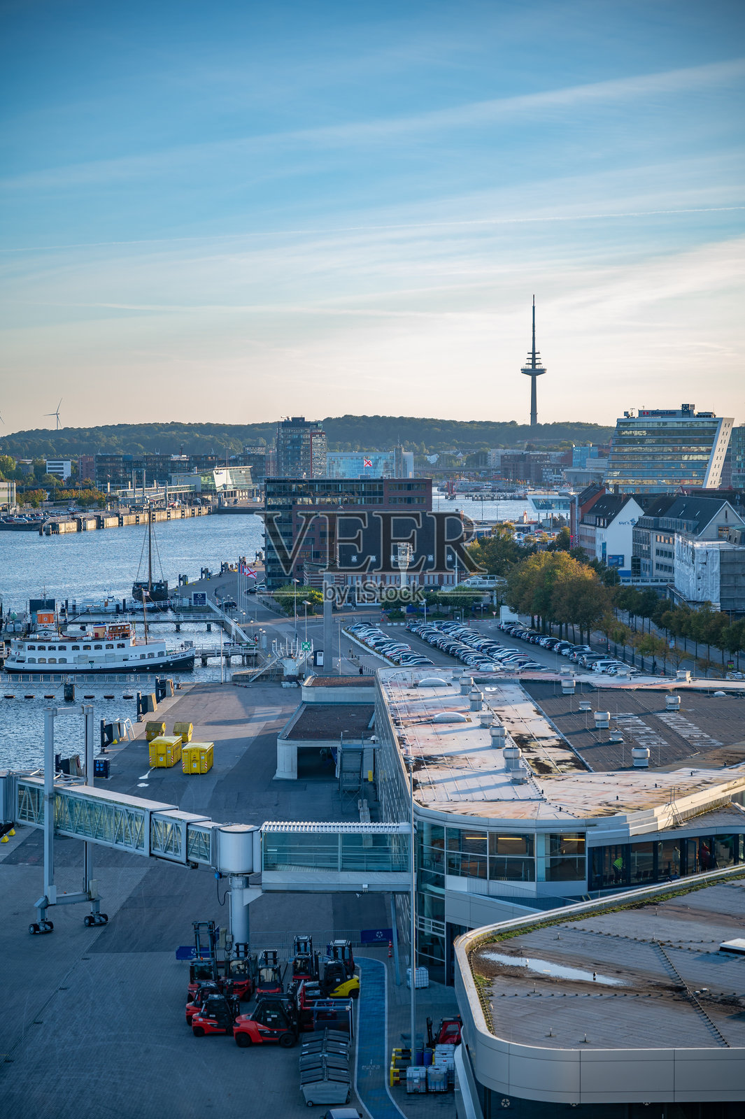 德国基尔港繁忙的景象，有渡轮码头、现代建筑和远处的高塔，背景是晴朗的天空，竖幅拍摄照片摄影图片