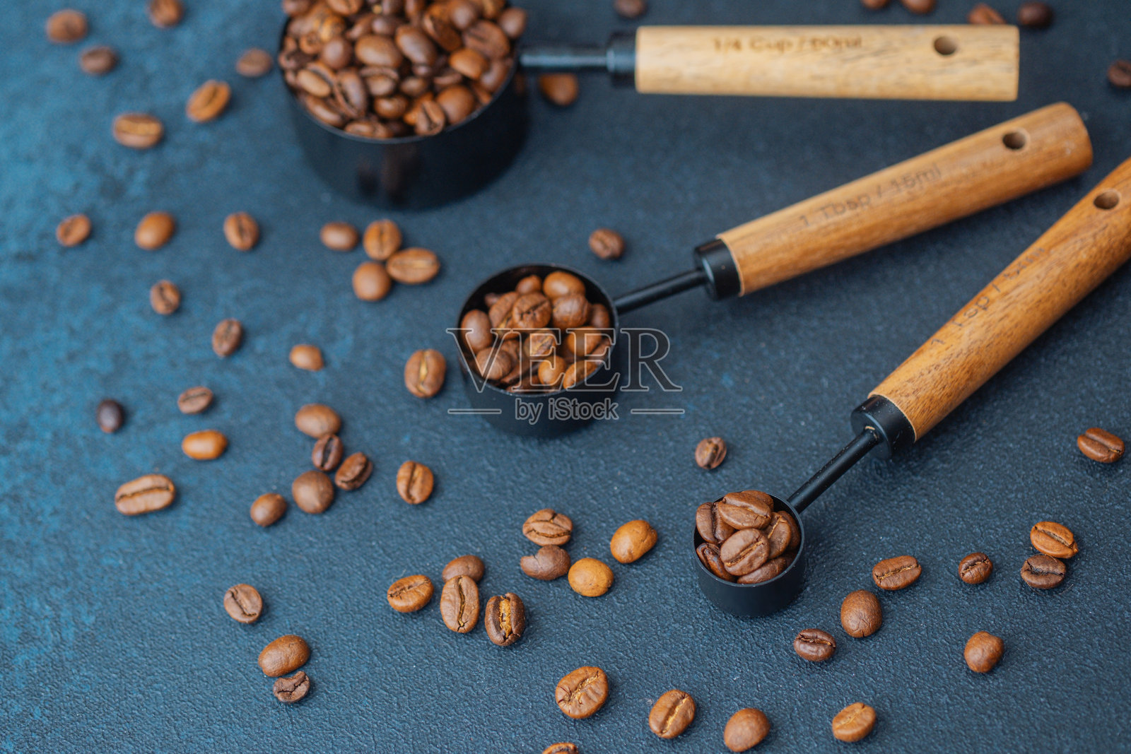 深色背景下量勺里的咖啡豆照片摄影图片