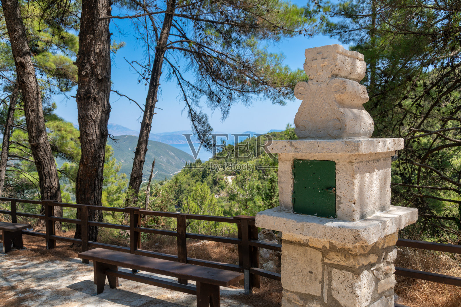 俯瞰森林覆盖的海岸山丘的带长凳的石砌神社照片摄影图片