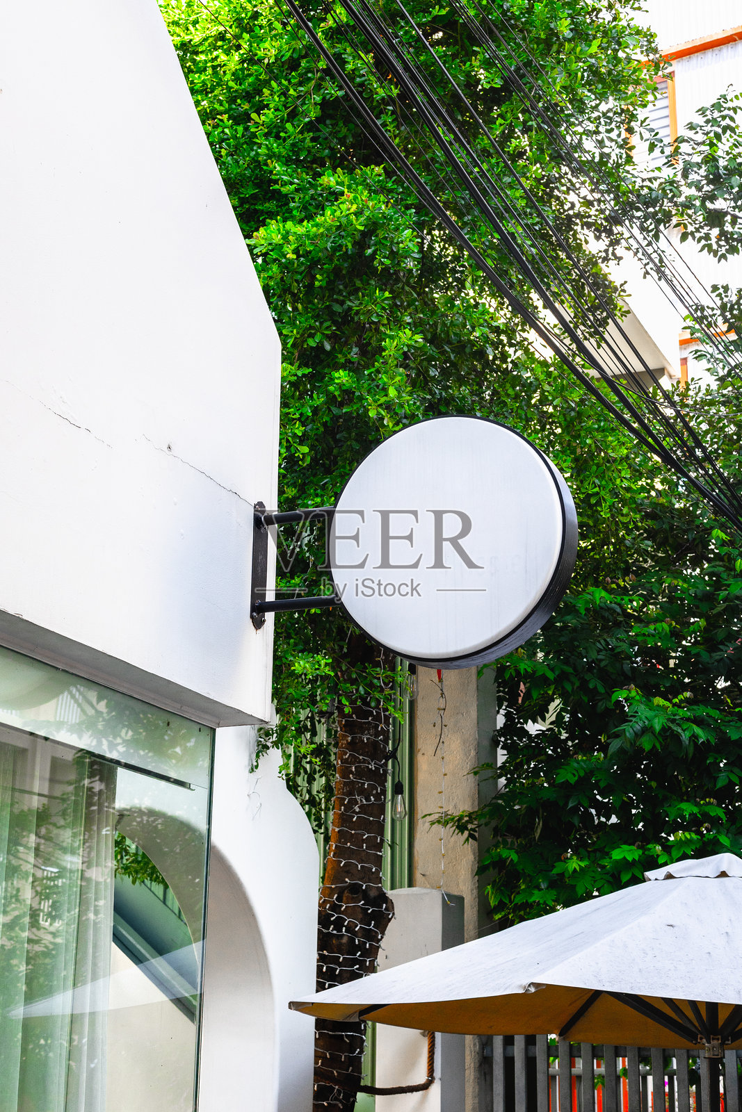 建筑外墙上的圆形空白招牌，周围有绿植照片摄影图片
