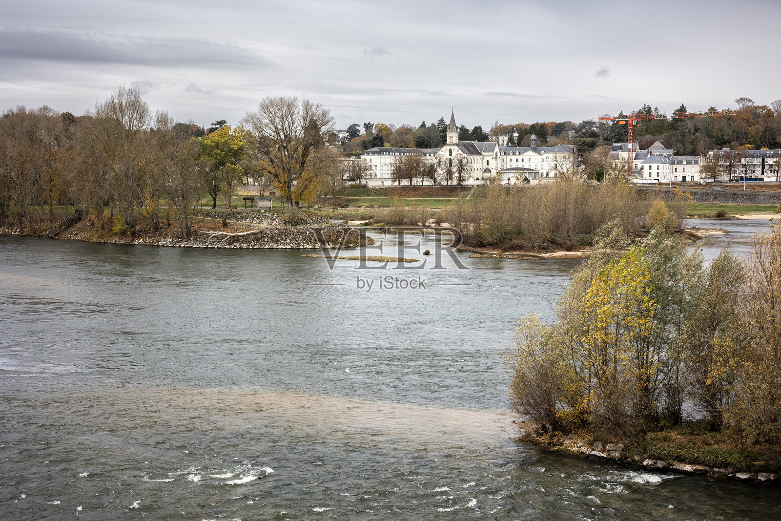 在多云的秋日天空下，俯瞰法国图尔的卢瓦尔河岛屿和威尔逊桥拱门，望向历史悠久的拉格兰德布雷特什修道院，构成一幅城市景观照片摄影图片