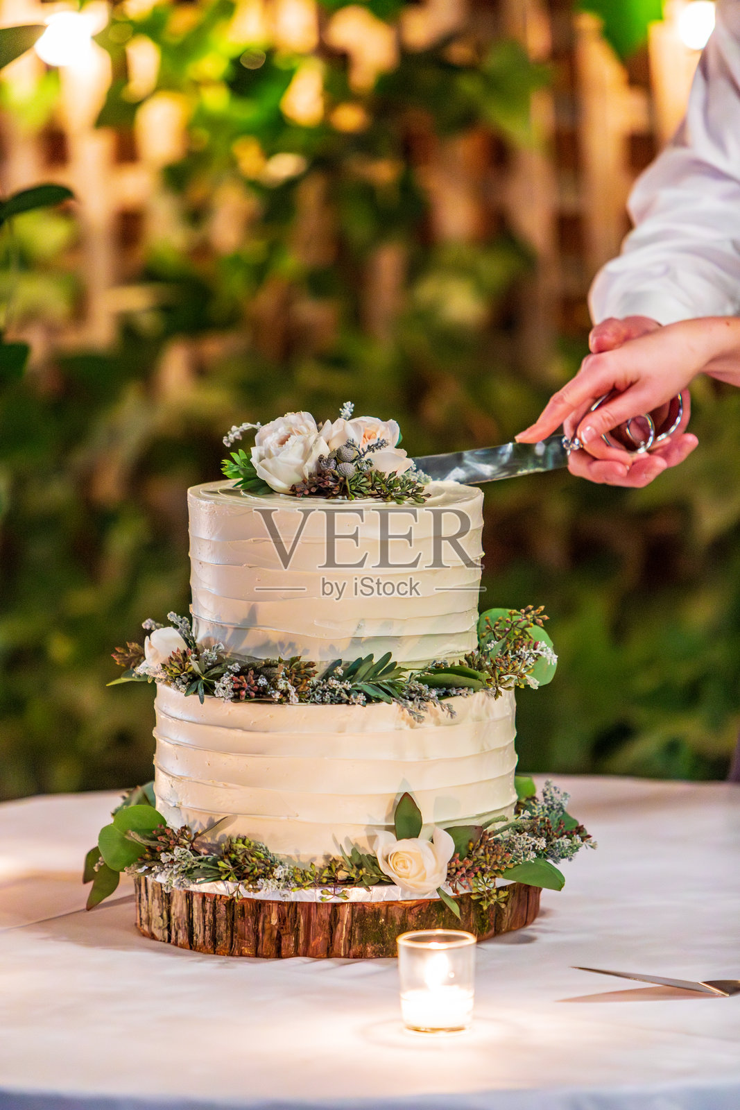 乡村风格的婚礼蛋糕正在被切割，装饰华丽，烛光映衬照片摄影图片