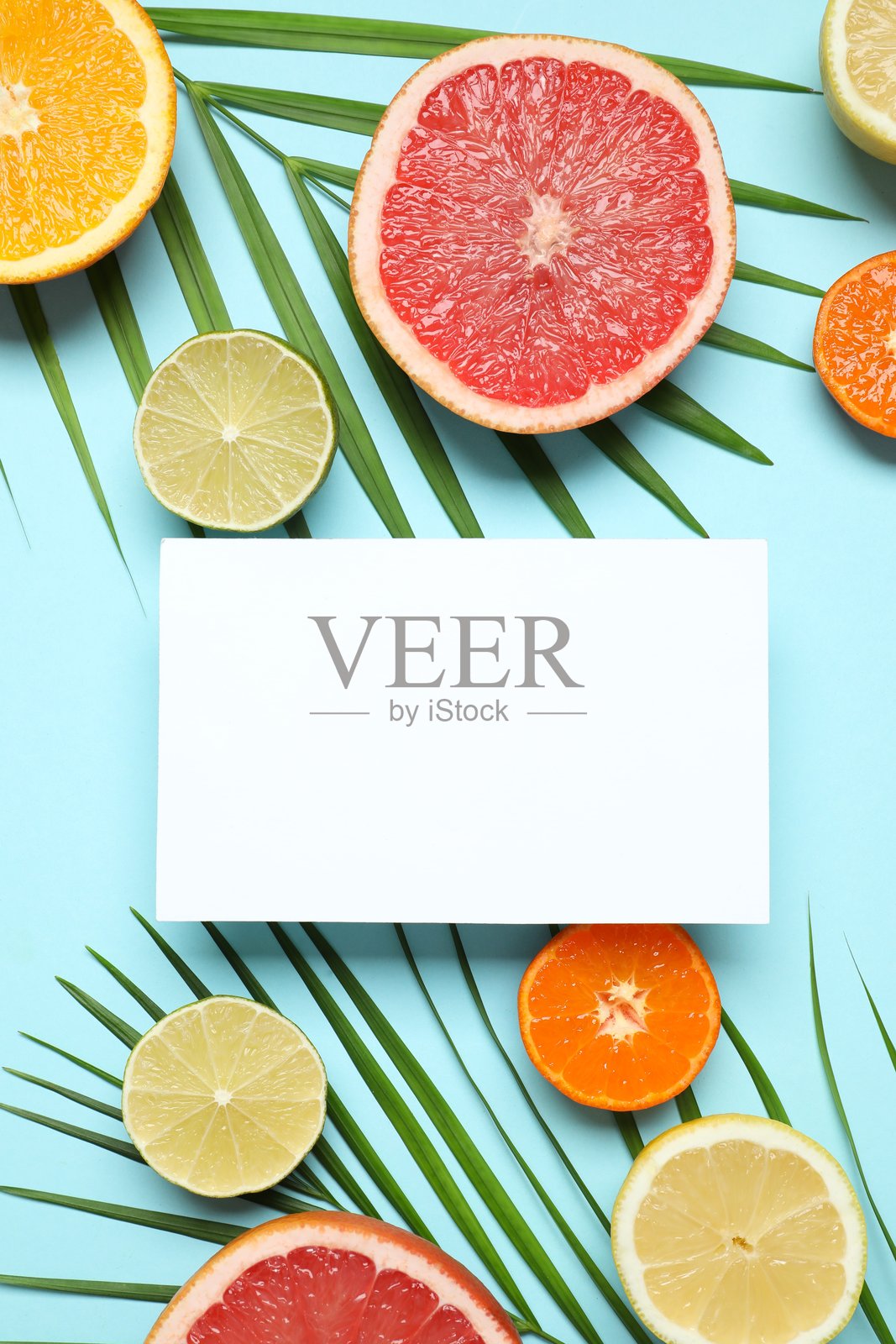 蓝底上切好的成熟多汁柑橘类水果和白色纸卡。柑橘图案。照片摄影图片