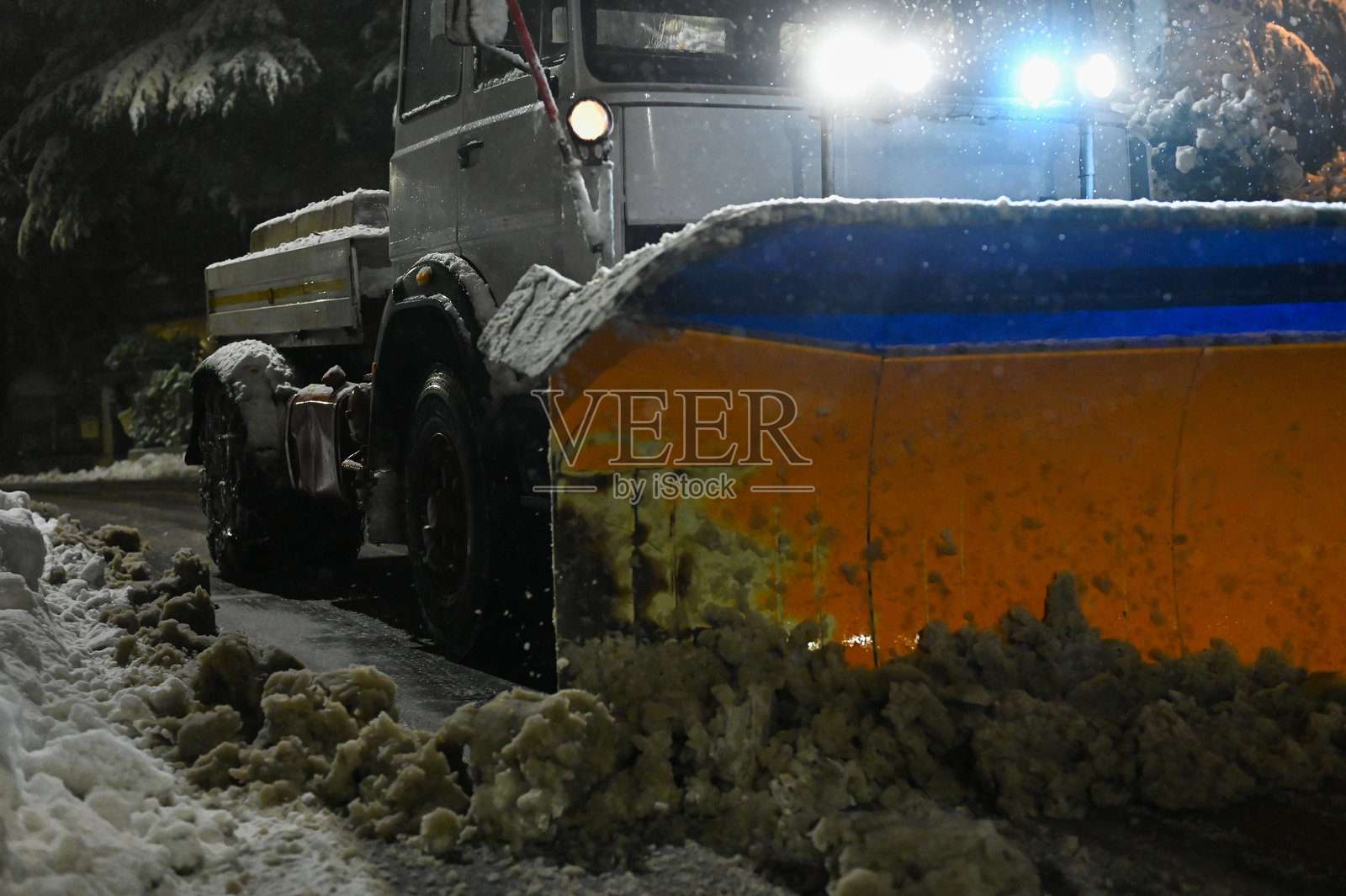 夜间，扫雪车正在清理道路上的积雪照片摄影图片