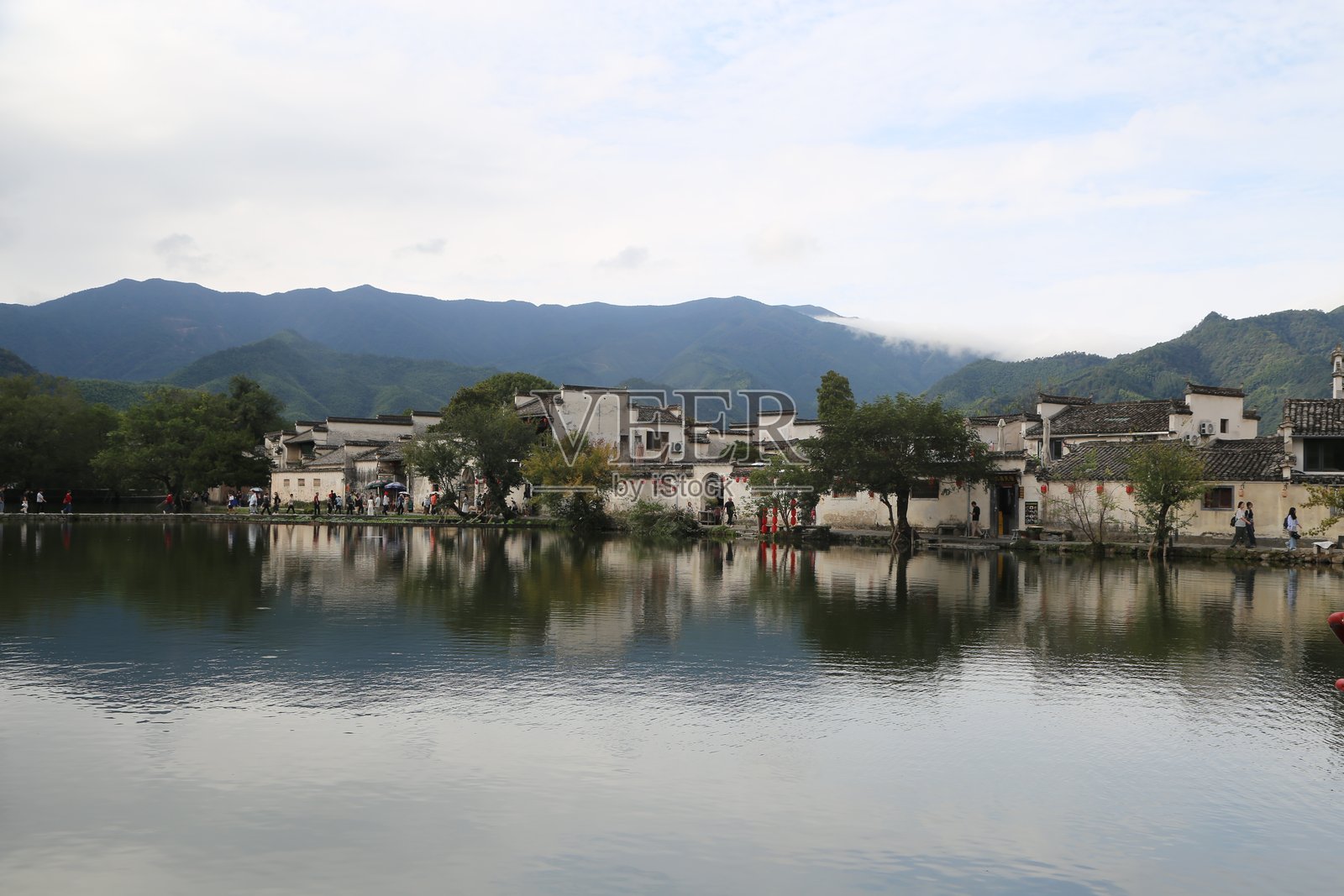 中国安徽省一个依山傍水的小村庄，水面两侧是白墙黑瓦的建筑。照片摄影图片