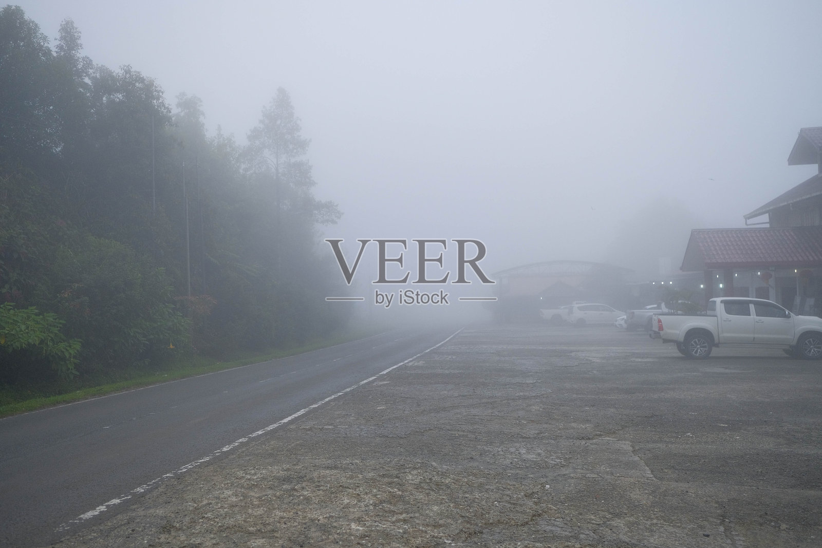 雾气缭绕的山路，停放着皮卡车和建筑物照片摄影图片