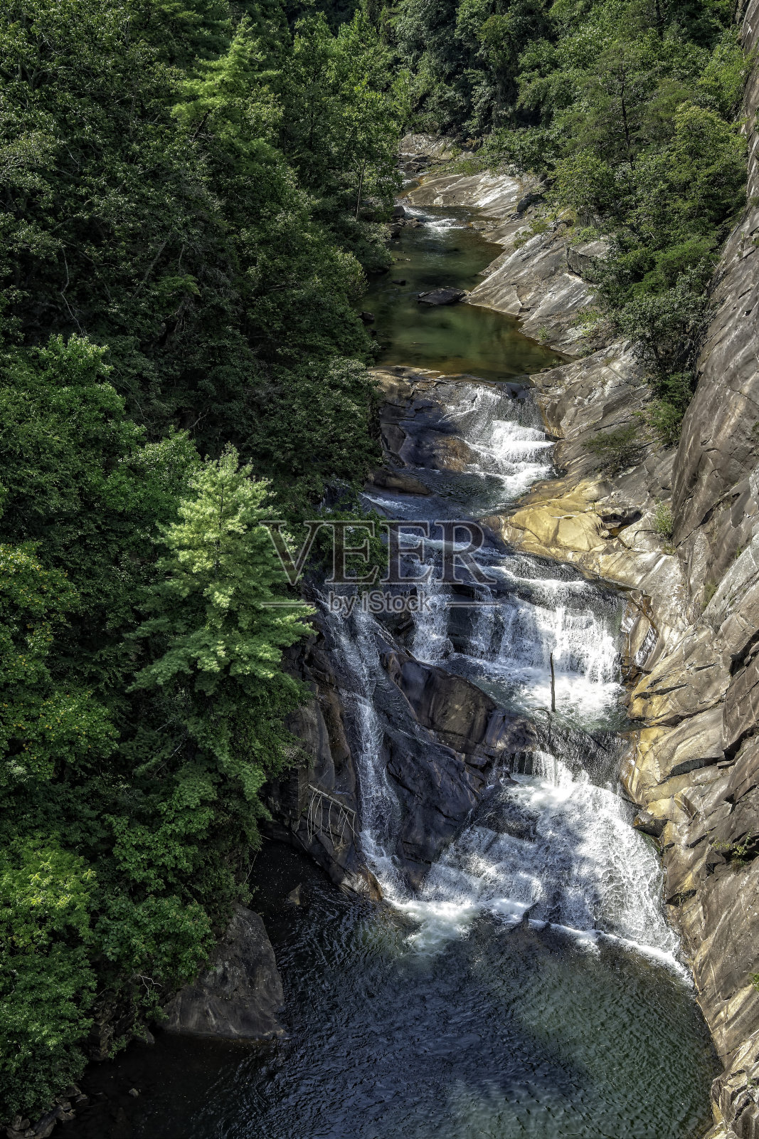 水在明朗的天空下，沿着岩石在郁郁葱葱的绿植环绕的塔卢拉河峡谷中倾泻而下照片摄影图片