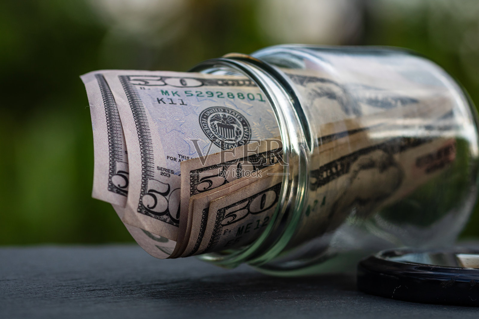 美元钞票存入玻璃罐。消费与经济。商业、小费、金融、储蓄、银行和人事概念照片摄影图片
