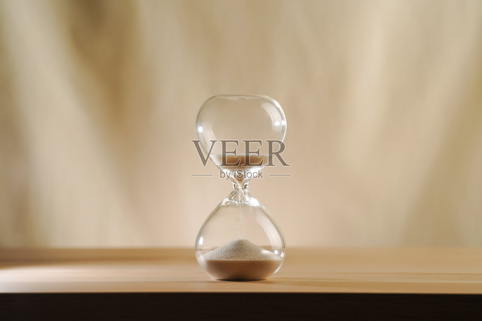极简风格的玻璃沙漏，在木质表面上，背景为米色，时间所剩无几照片摄影图片