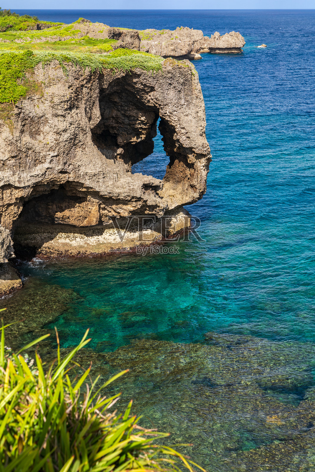 冲绳万座毛：晴朗夏日下，碧蓝与绿松石色海水的渐变以及悬崖峭壁。照片摄影图片