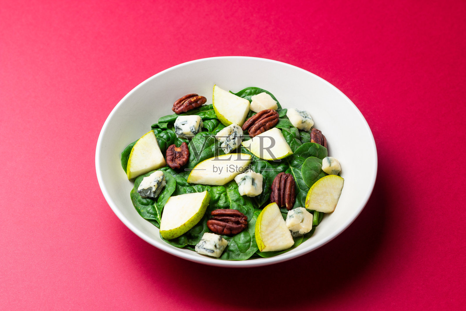 菠菜、蓝纹奶酪、梨和坚果沙拉。健康饮食。素食。照片摄影图片