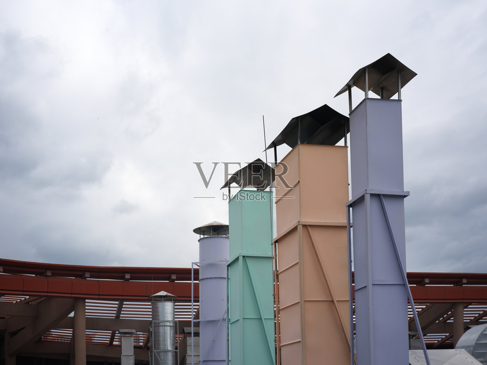 多云天空映衬下的彩色工业烟囱建筑照片摄影图片