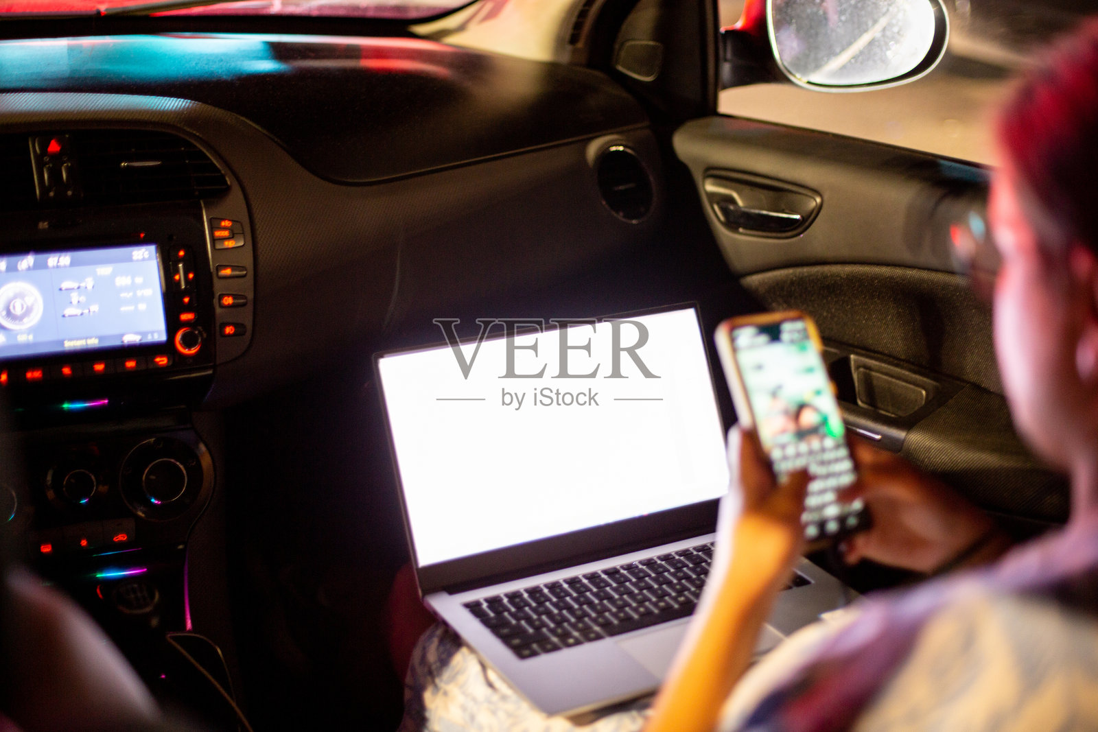 夜晚在车内，一个人同时使用笔记本电脑和智能手机处理多项任务照片摄影图片