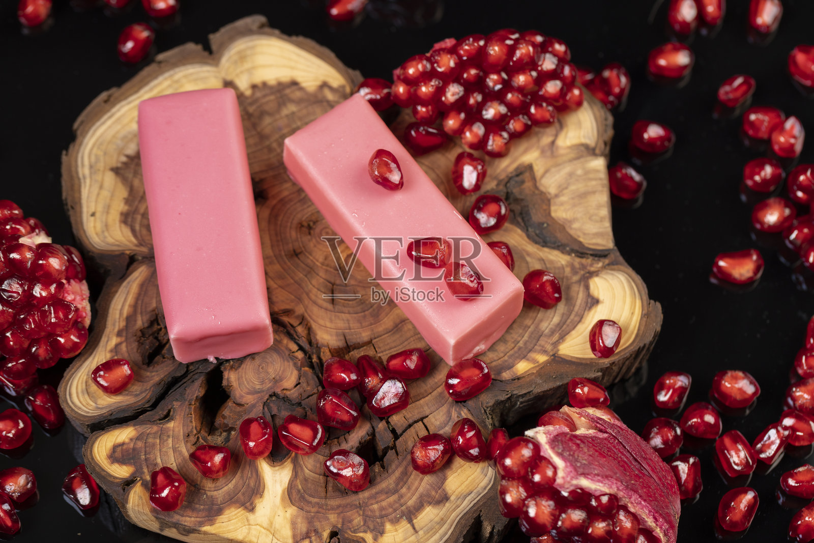 红熟去皮石榴，配以粉色糖霜包裹的大颗多汁奶酪，以及红石榴籽和奶酪甜点照片摄影图片