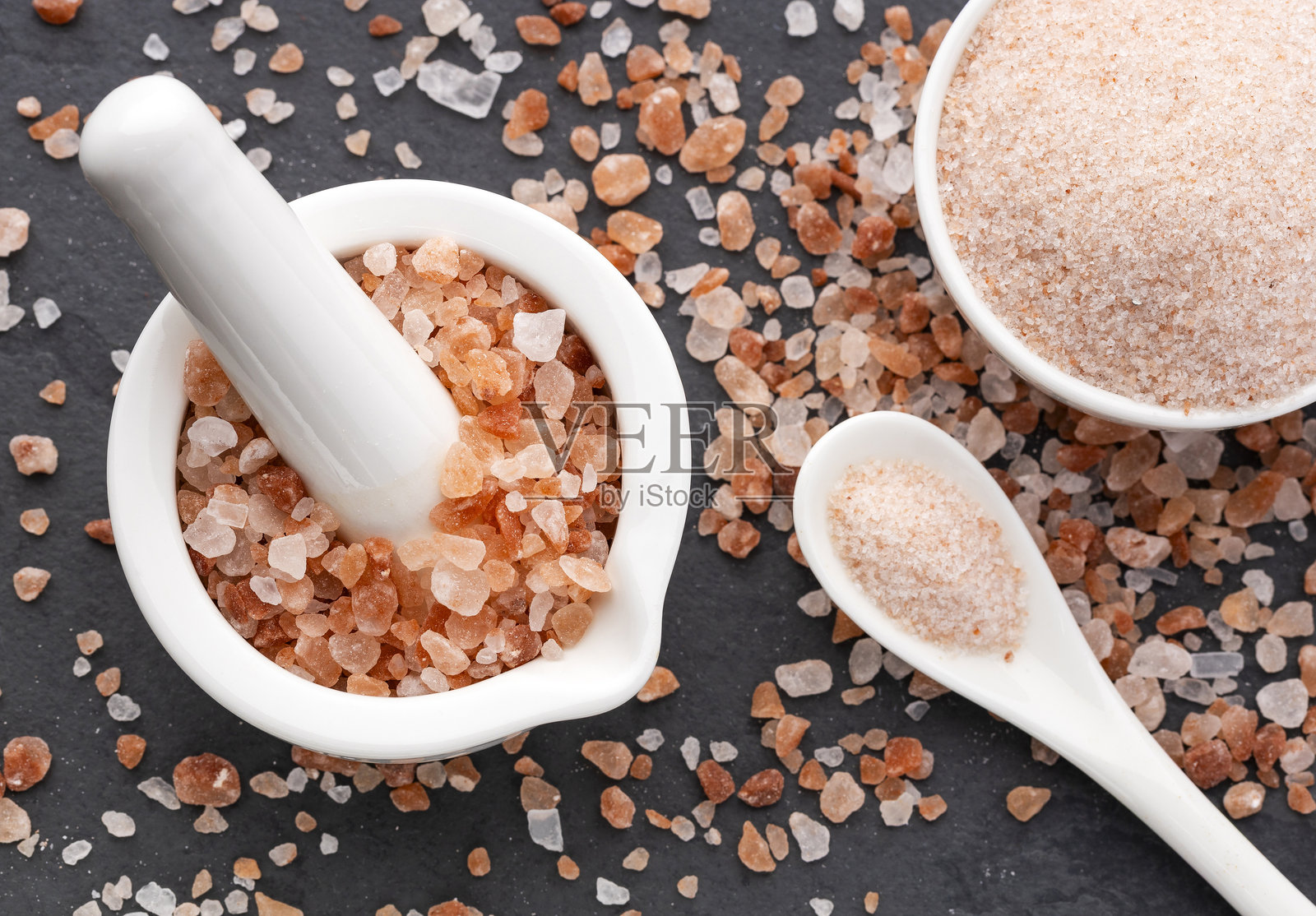碗中纯净细致的喜马拉雅盐，配有勺子和研杵 - 粉色晶体。照片摄影图片