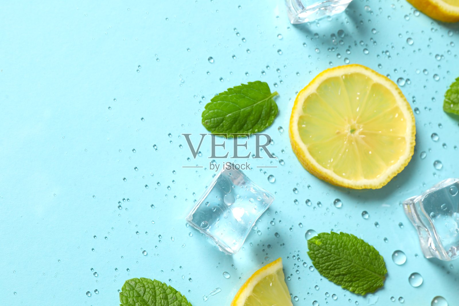俯拍蓝底上孤立的冰块、柠檬、薄荷和水滴堆，留有空白空间照片摄影图片