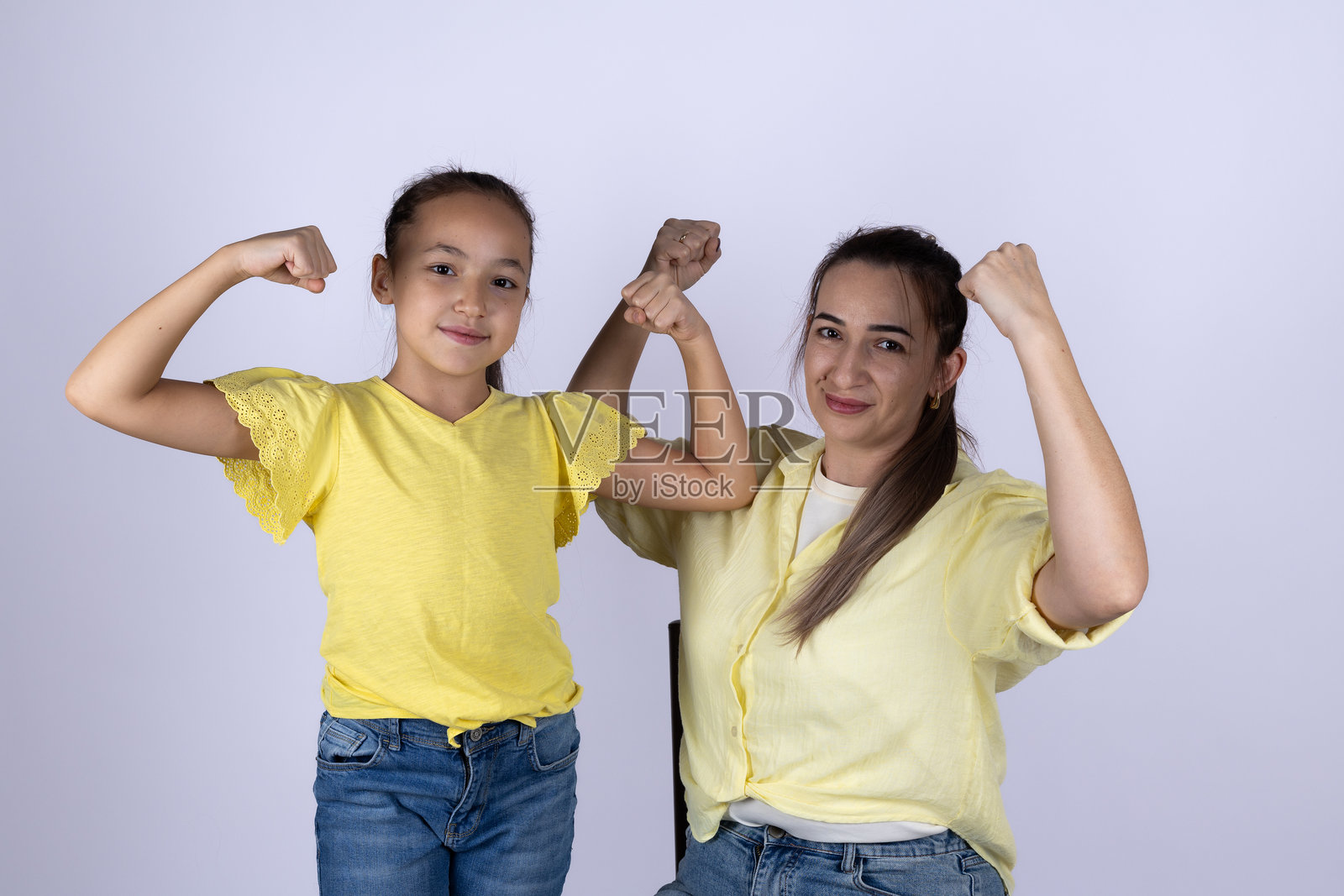 一位女士和一位小女孩正对着镜头微笑，展示着她们的手臂肌肉照片摄影图片