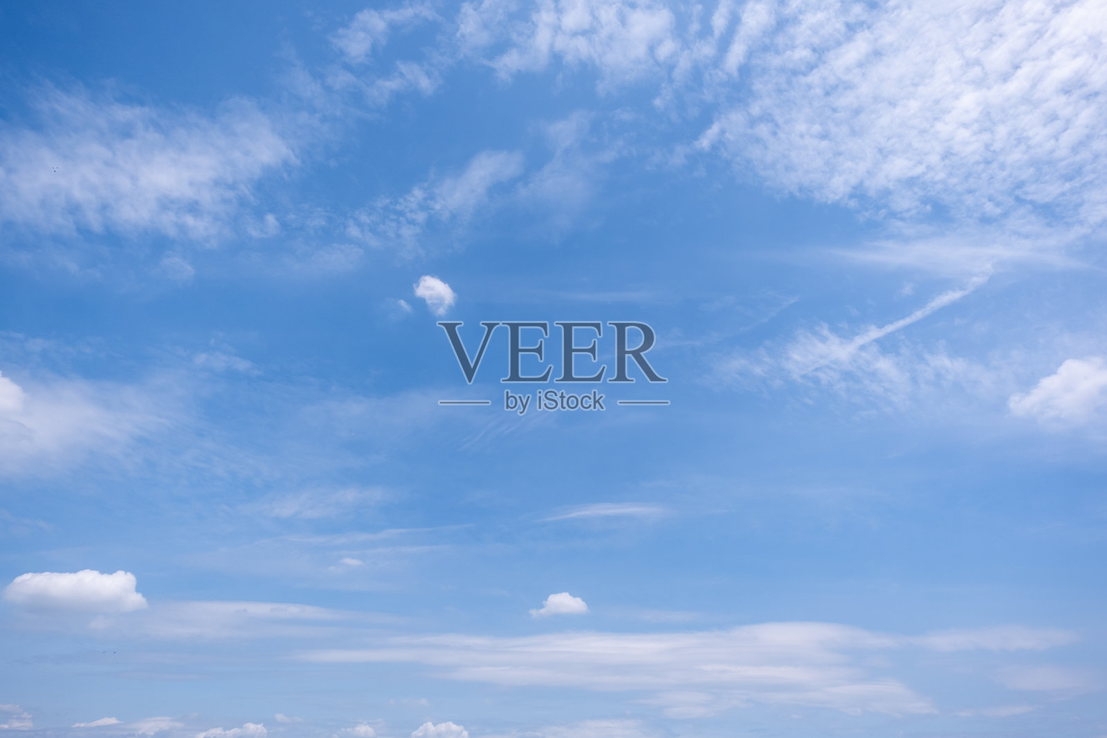 蔚蓝天空与朵朵白云的全景视图，蔚蓝的天空背景点缀着几朵微小的云彩。洁白的蓬松云朵漂浮在蔚蓝的天空中。这张迷人的样片捕捉了天空与云朵令人陶醉的美丽。照片摄影图片