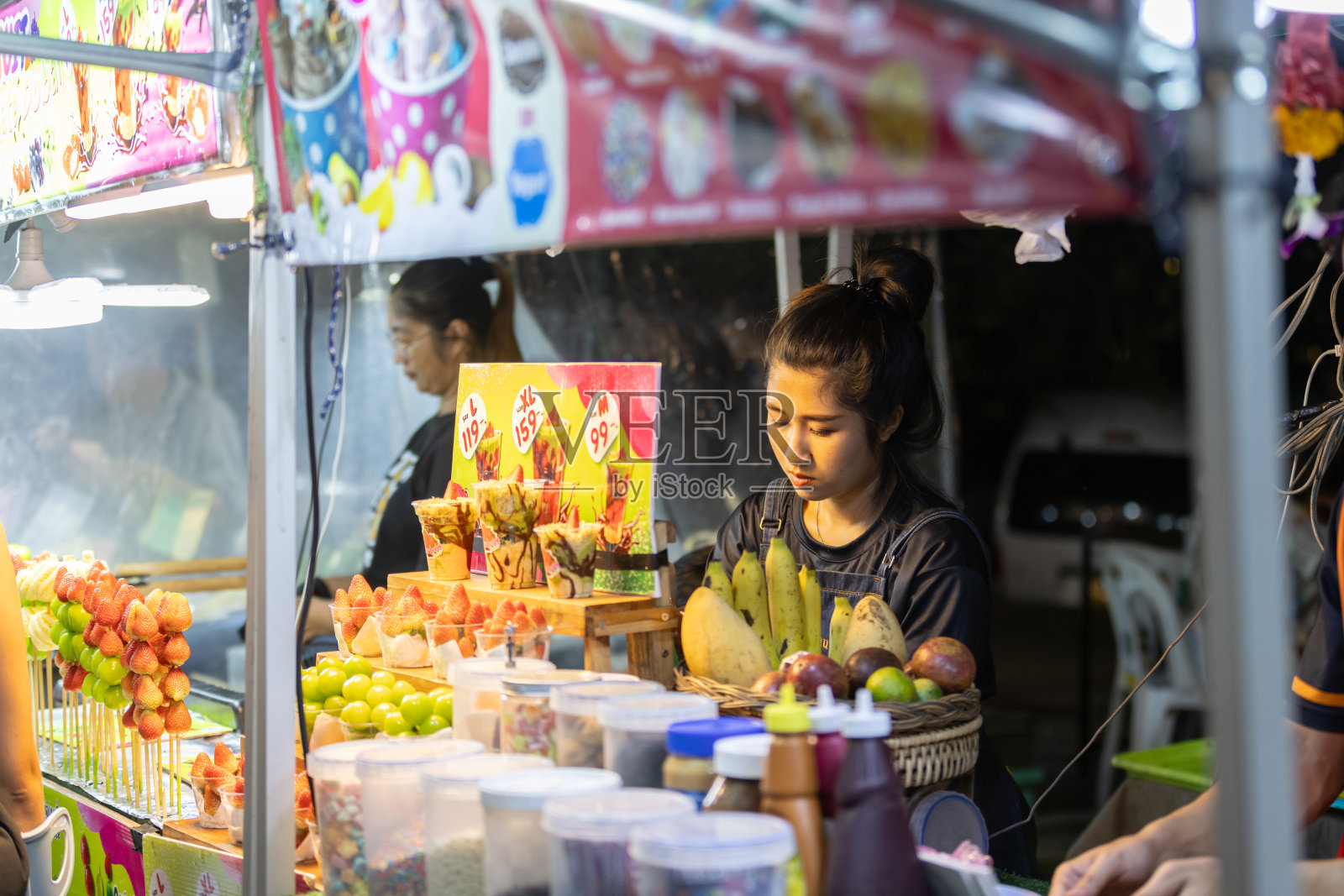 泰国女子在夜市为顾客准备街头美食。照片摄影图片